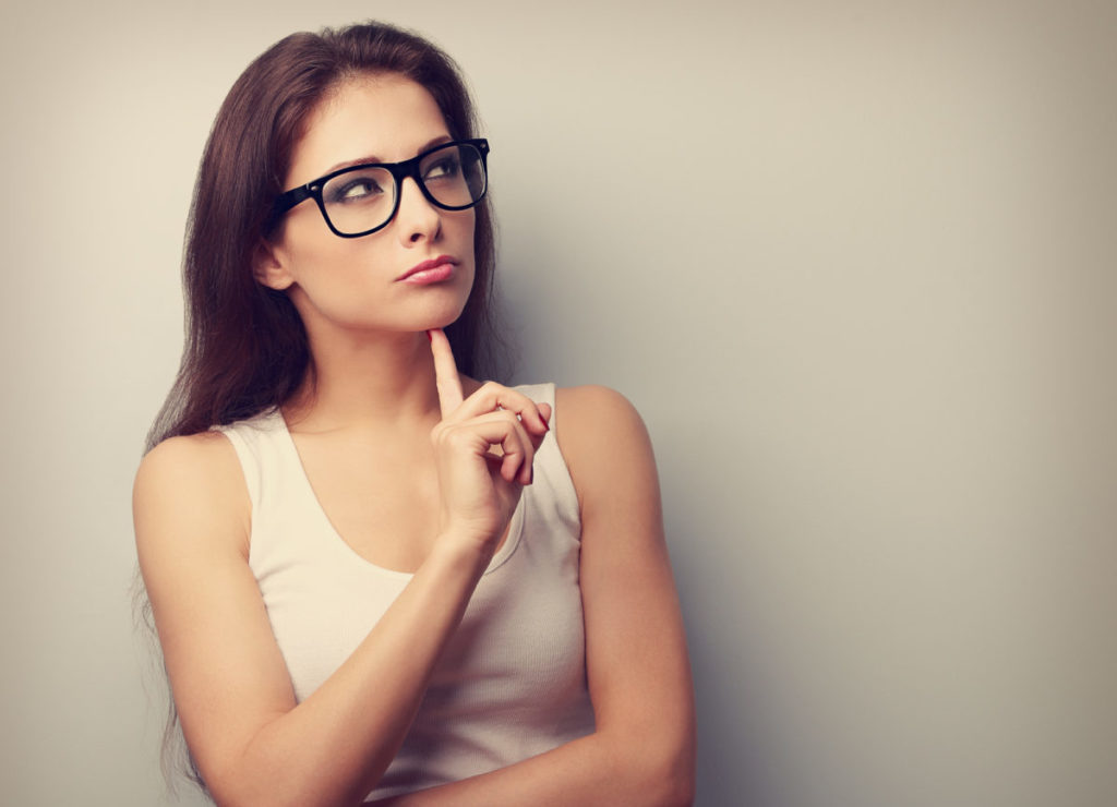 Serious fun thinking young woman looking up on empty copy space