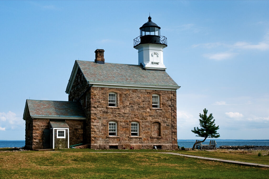 Lighthouse behind stone building on island in Norwalk CT during Sheffield Island Wedding
