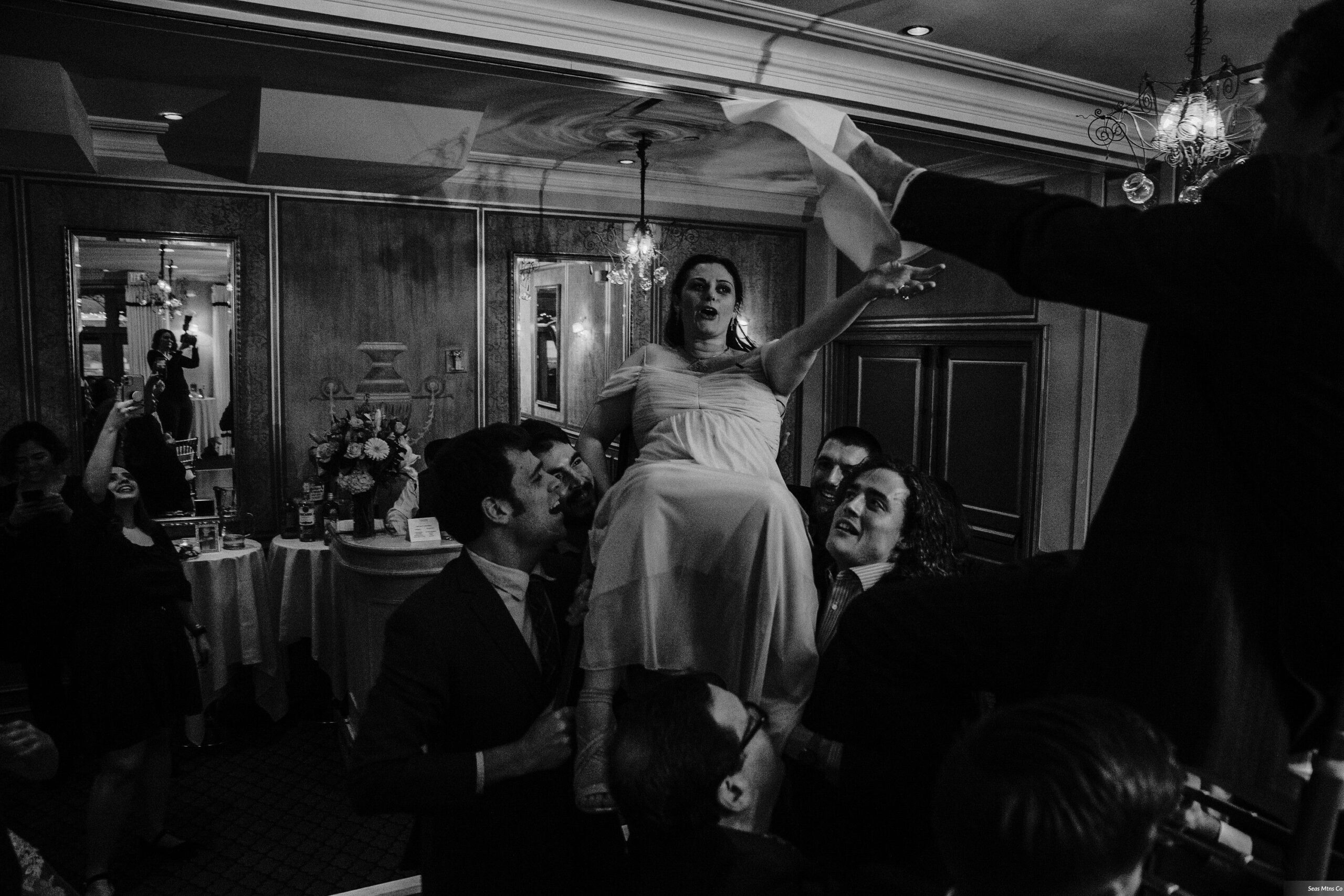 Bride and Groom held up on chairs during hora on dancefloor at Lescale wedding in Greenwich CT