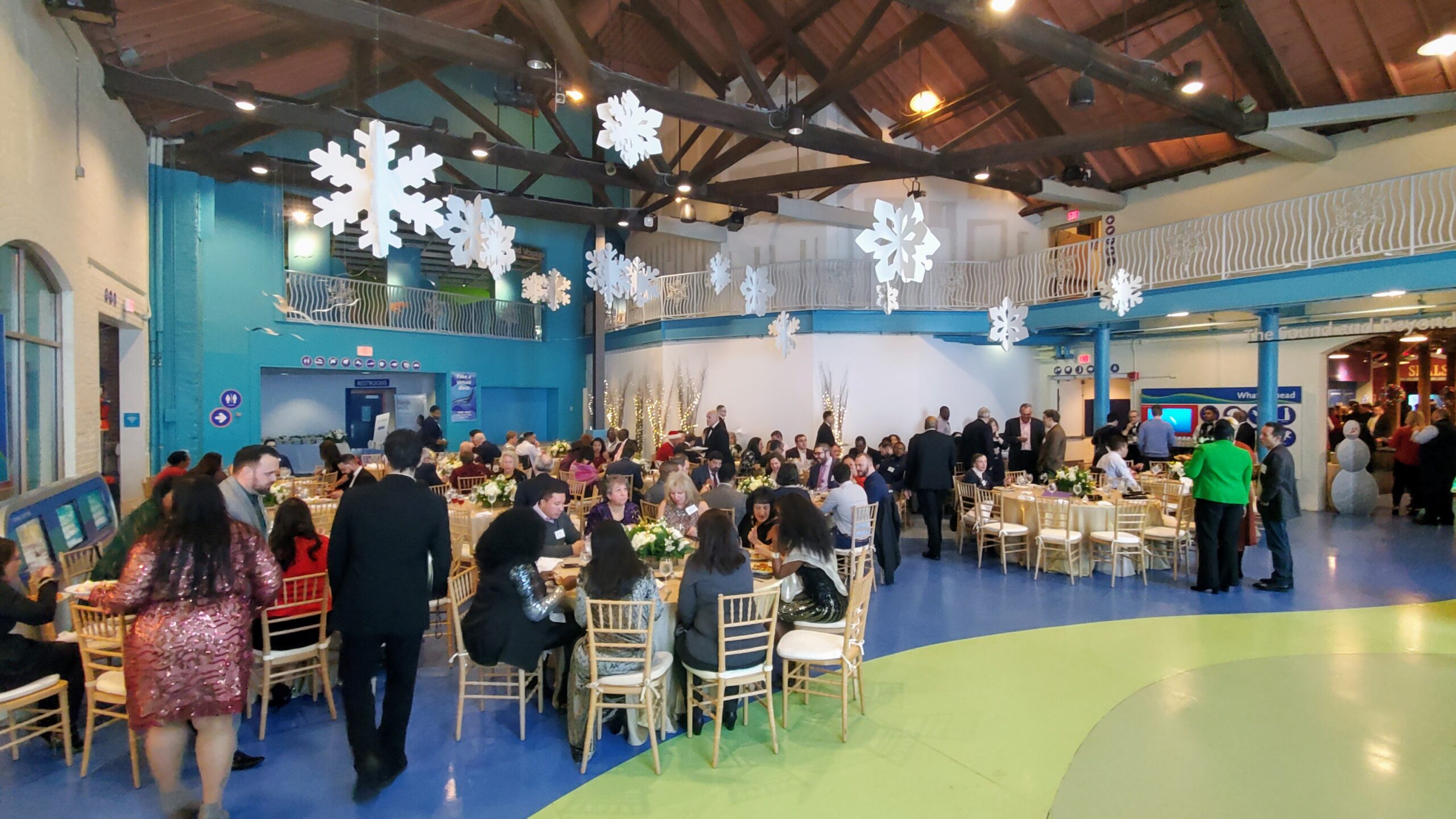 Corporatate holiday party at the Maritime Aquarium showing guests seated for dinner at tables in reception hall
