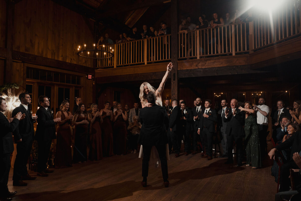 Bride held up in the air by groom on dancefloor surrounded by friends for their first dance The Preserve at Chocorua in Tamworth NH