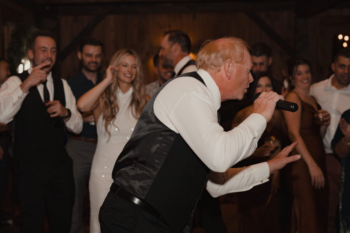 Father of bride holding microphone during lip sync performance at daughters wedding at The Preserve at Chocorua in Tamworth NH